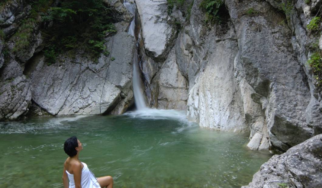 Frau in Tuch posiert vor einem Wasserfall