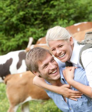Glückliches Paar beim Wandern zwischen Kühen