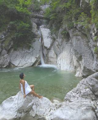 Frau posiert vor Wasserfall